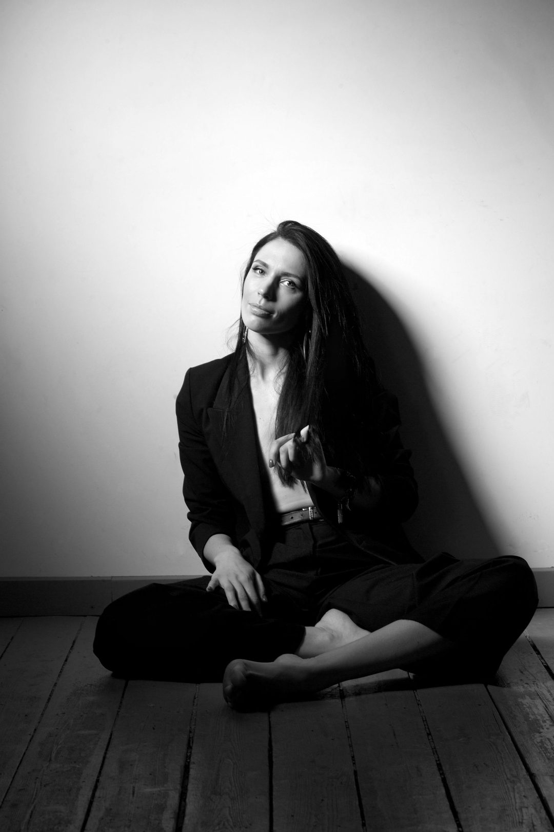 Seated in tailored suit against wall